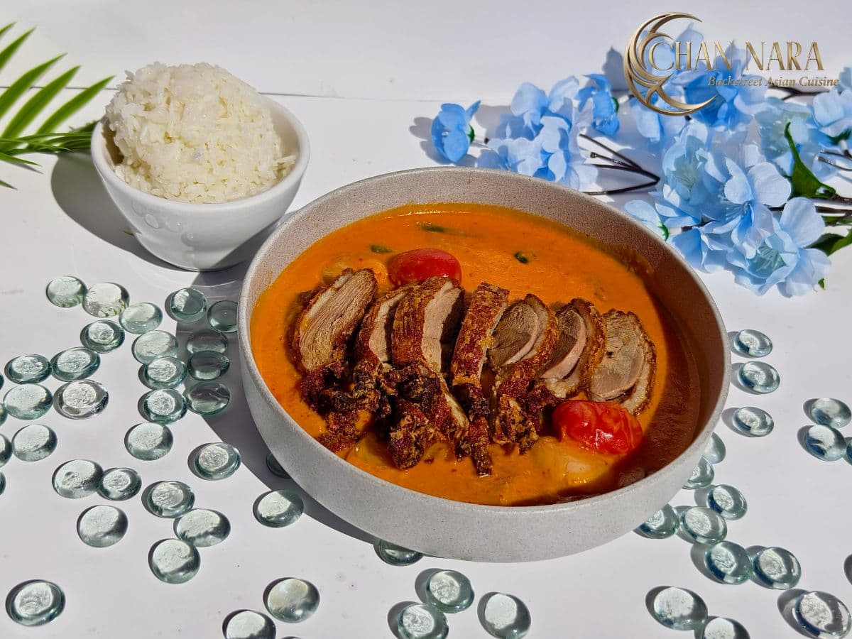 Roasted Duck Curry with roasted duck, coconut curry broth, lychees, pineapple, cherry tomatoes, and Thai basil